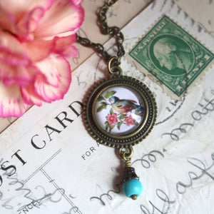 Simple beaded pendant necklace with antique image of a bluebird sitting on a rose